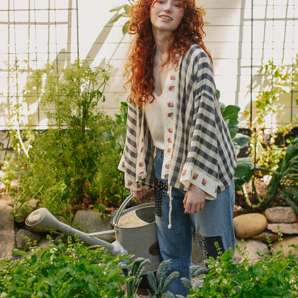 
                  
                    Model wearing Happy Days pixie cut kimono featuring heritage gingham, vintage strawberries, and a cross-stitch patch inspired by an 1836 sampler – Market of Stars.
                  
                