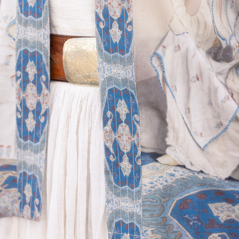 
                  
                    Model wearing the Head in the Clouds Opera Duster featuring Liotard’s portrait of his wife with Turkish textiles, starry sleeves, and poetic script – Market of Stars.
                  
                