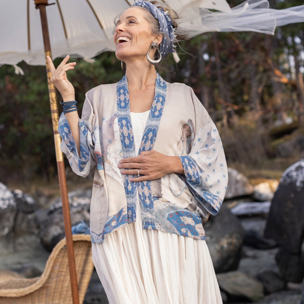 
                  
                    Model wearing the Head in the Clouds Opera Duster featuring Liotard’s portrait of his wife with Turkish textiles, starry sleeves, and poetic script – Market of Stars.
                  
                