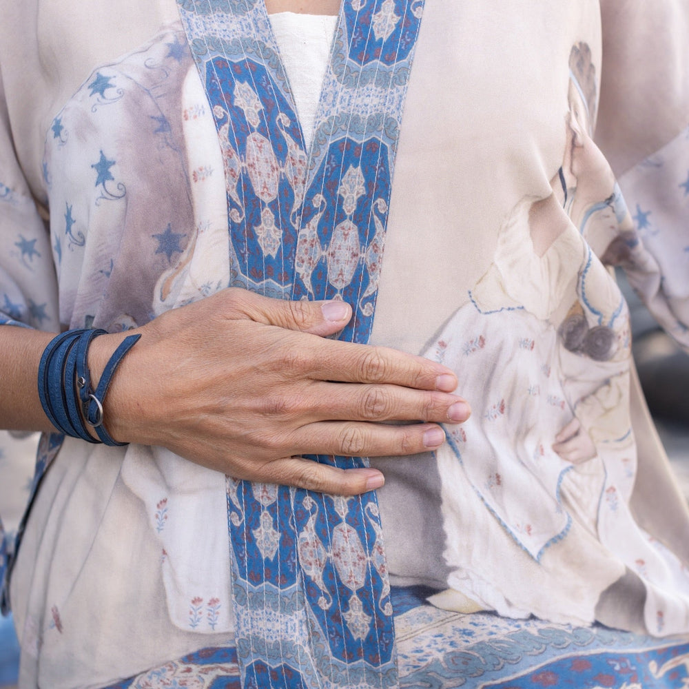 
                  
                    Model wearing the Head in the Clouds Opera Duster featuring Liotard’s portrait of his wife with Turkish textiles, starry sleeves, and poetic script – Market of Stars.
                  
                