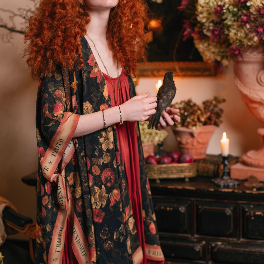 
                  
                    Model wearing a flowy bamboo-viscose duster featuring a collage of antique artwork with romance, loyalty, and old-world beauty - Market of Stars
                  
                