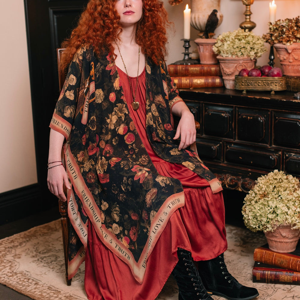 
                  
                    Model wearing a flowy bamboo-viscose duster featuring a collage of antique artwork with romance, loyalty, and old-world beauty - Market of Stars
                  
                