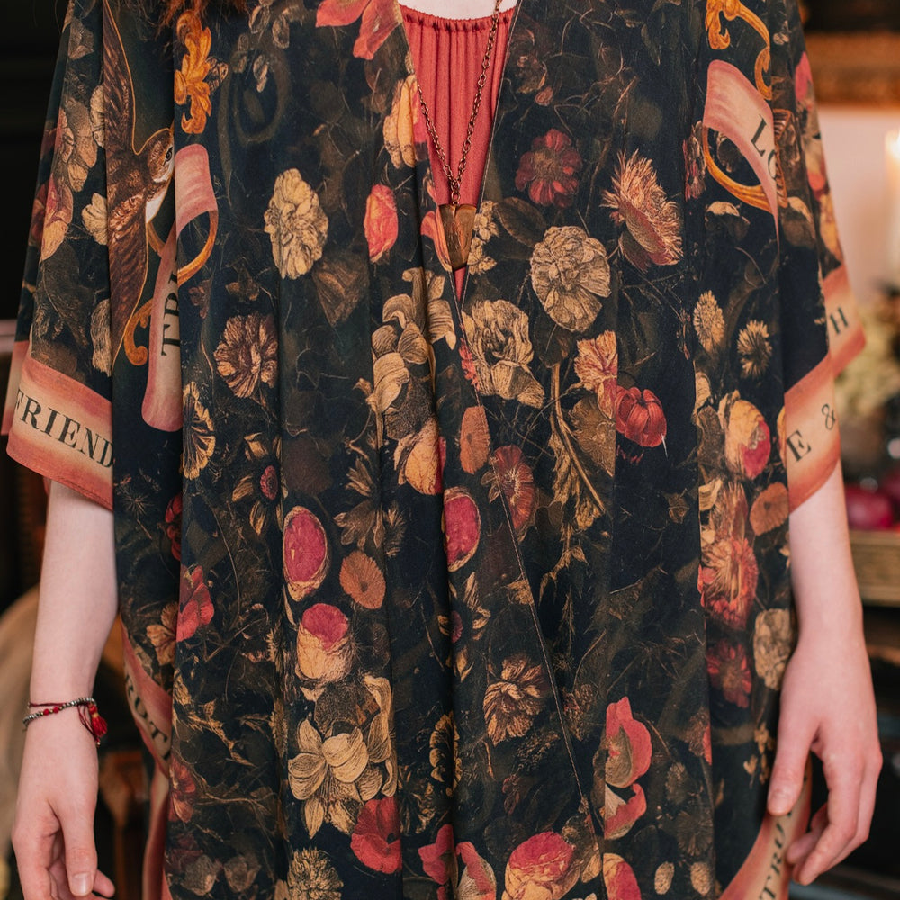 
                  
                    Model wearing a flowy bamboo-viscose duster featuring a collage of antique artwork with romance, loyalty, and old-world beauty - Market of Stars
                  
                