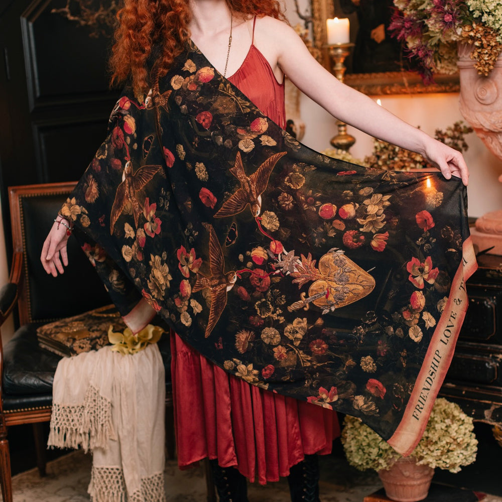 Model wearing a bamboo-viscose scarf featuring a collage of antique artwork that celebrates the bonds in our lives that endure — love, truth, and loyal friends!