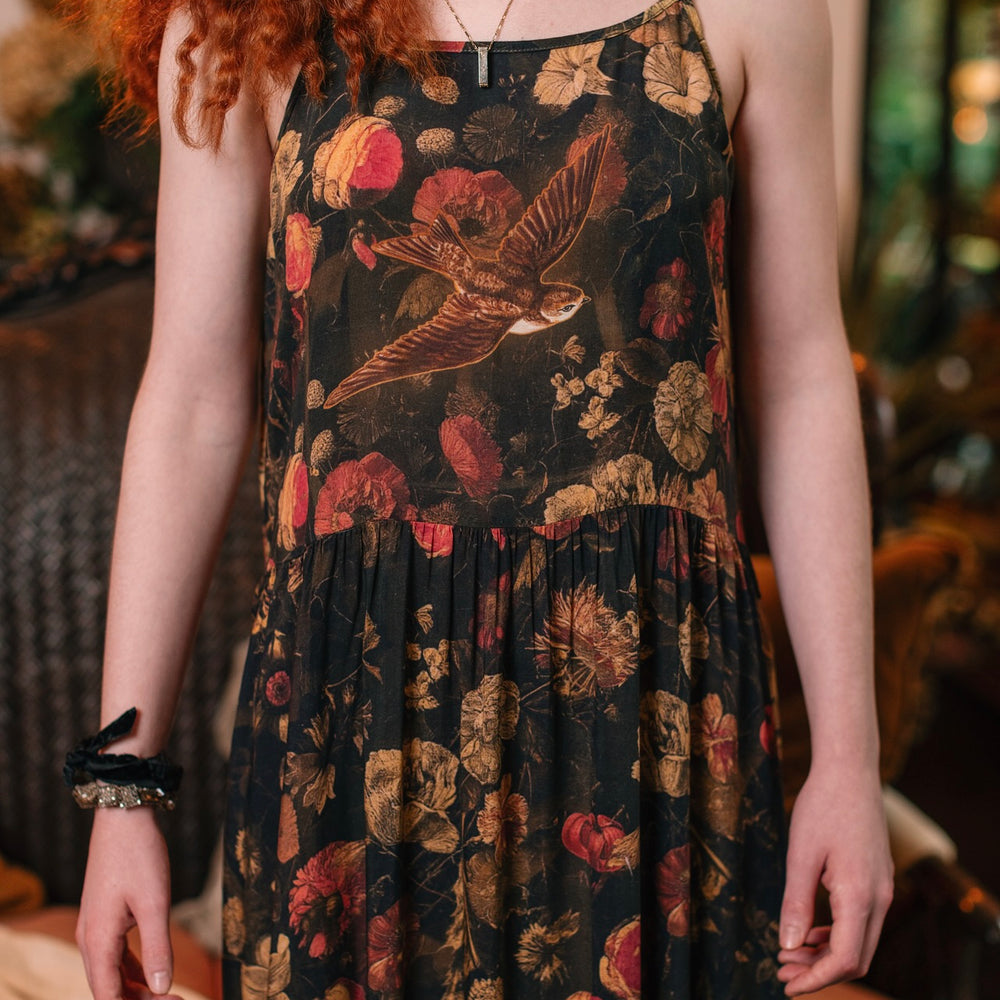 
                  
                    Model wearing a maxi-length bamboo-viscose slip dress featuring a collage of antique artwork with romance, loyalty, and old-world beauty - Market of Stars
                  
                