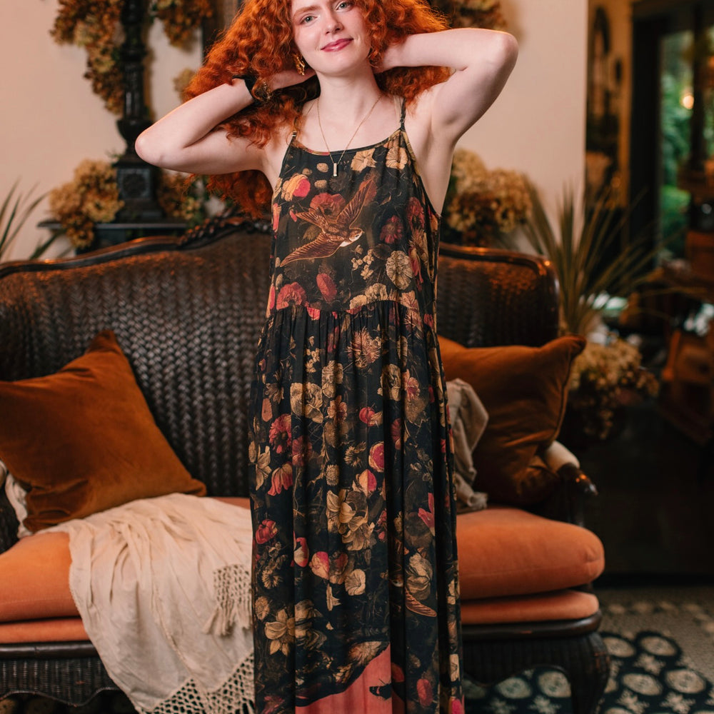 
                  
                    Model wearing a maxi-length bamboo-viscose slip dress featuring a collage of antique artwork with romance, loyalty, and old-world beauty - Market of Stars
                  
                