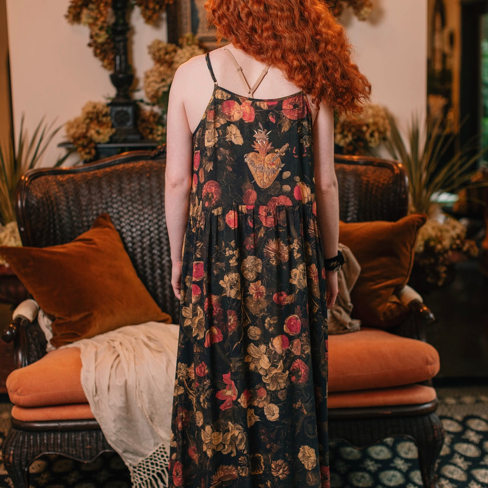 
                  
                    Model wearing a maxi-length bamboo-viscose slip dress featuring a collage of antique artwork with romance, loyalty, and old-world beauty - Market of Stars
                  
                