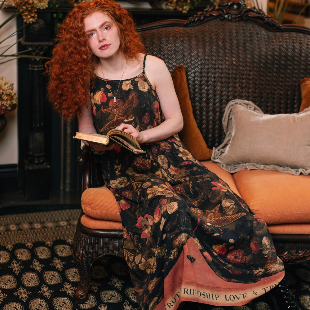 
                  
                    Model wearing a maxi-length bamboo-viscose slip dress featuring a collage of antique artwork with romance, loyalty, and old-world beauty - Market of Stars
                  
                