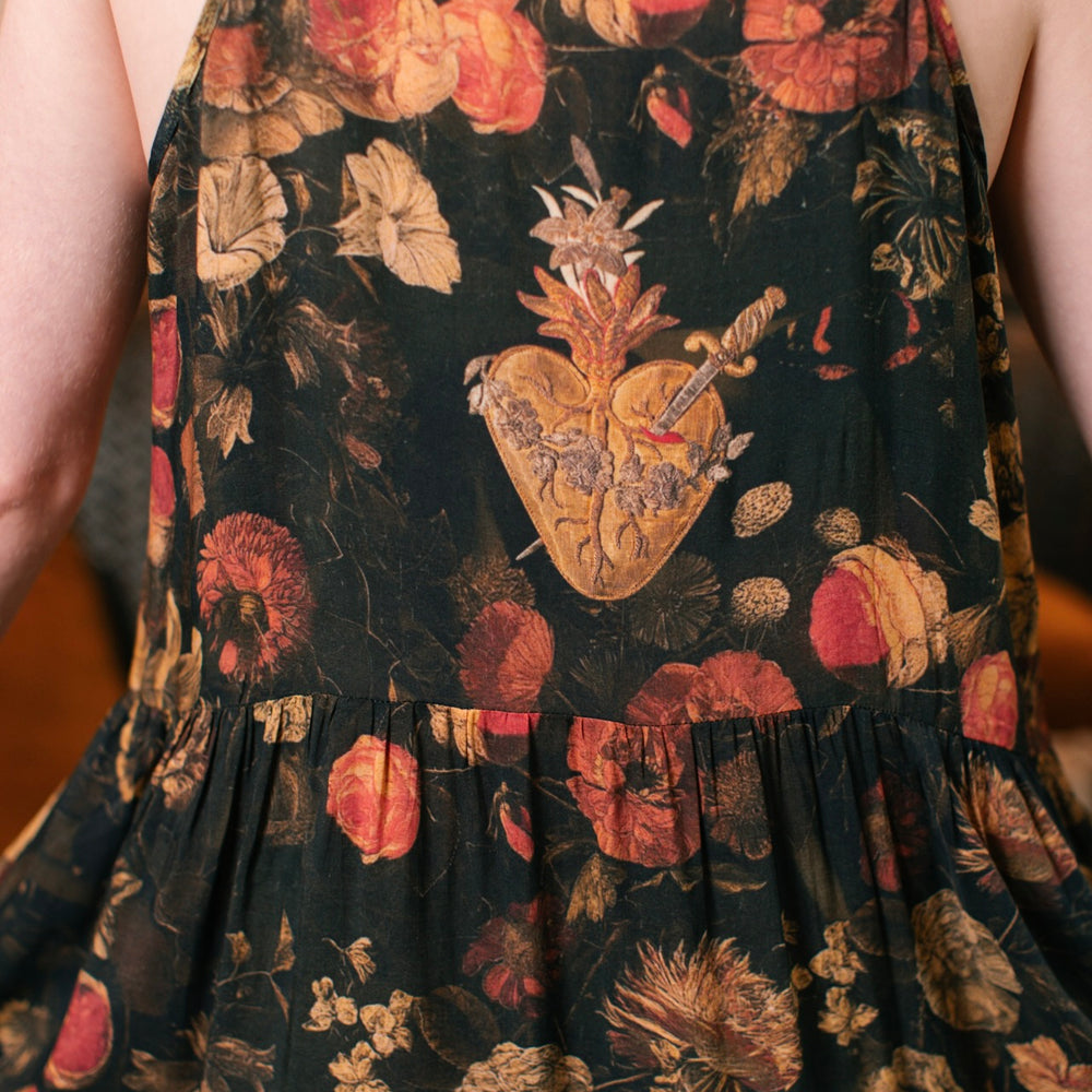 
                  
                    Model wearing a maxi-length bamboo-viscose slip dress featuring a collage of antique artwork with romance, loyalty, and old-world beauty - Market of Stars
                  
                
