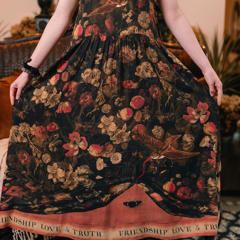 
                  
                    Model wearing a maxi-length bamboo-viscose slip dress featuring a collage of antique artwork with romance, loyalty, and old-world beauty - Market of Stars
                  
                