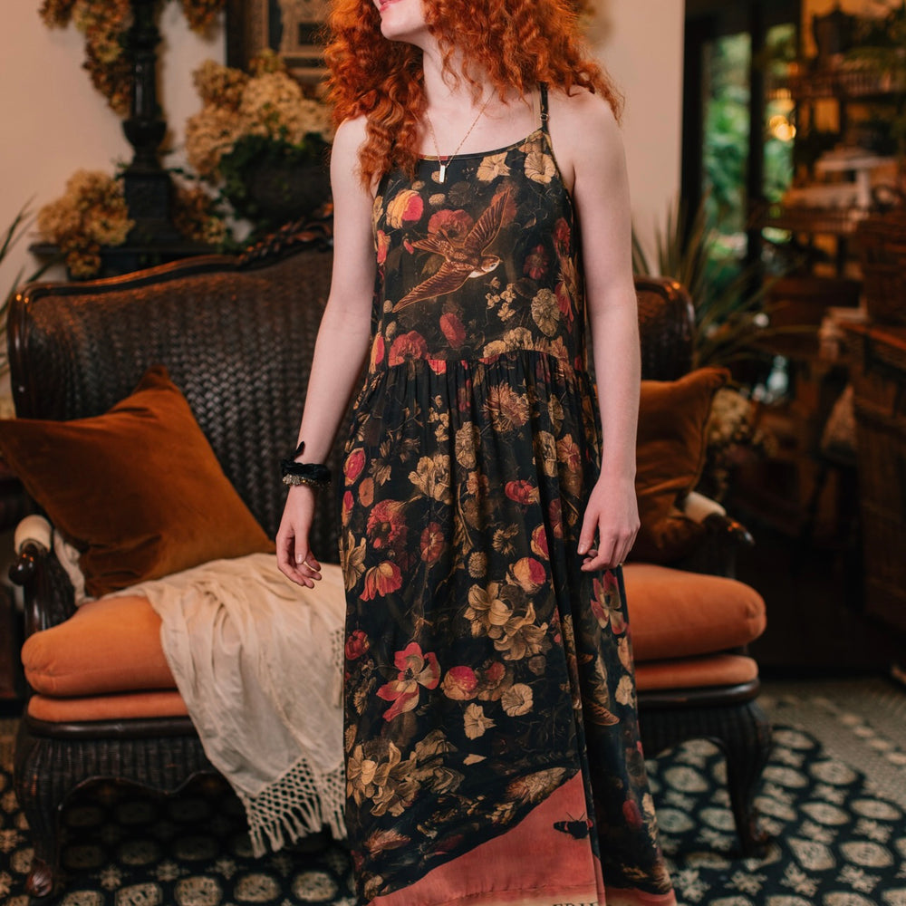 
                  
                    Model wearing a maxi-length bamboo-viscose slip dress featuring a collage of antique artwork with romance, loyalty, and old-world beauty - Market of Stars
                  
                