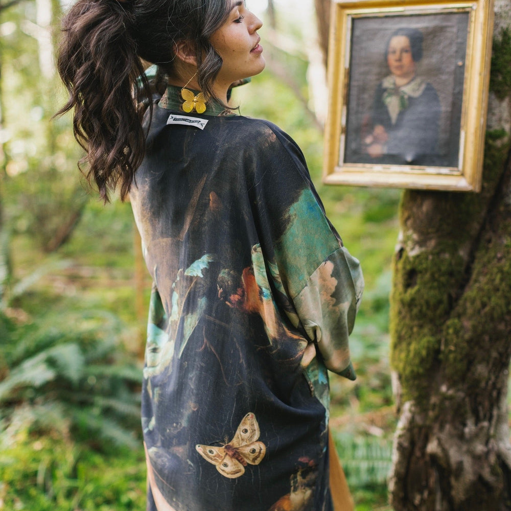 
                  
                    Model wearing the Heartwork Opera Duster featuring Artemisia Gentileschi’s self-portrait surrounded by forest, birds, and butterflies – Market of Stars.
                  
                
