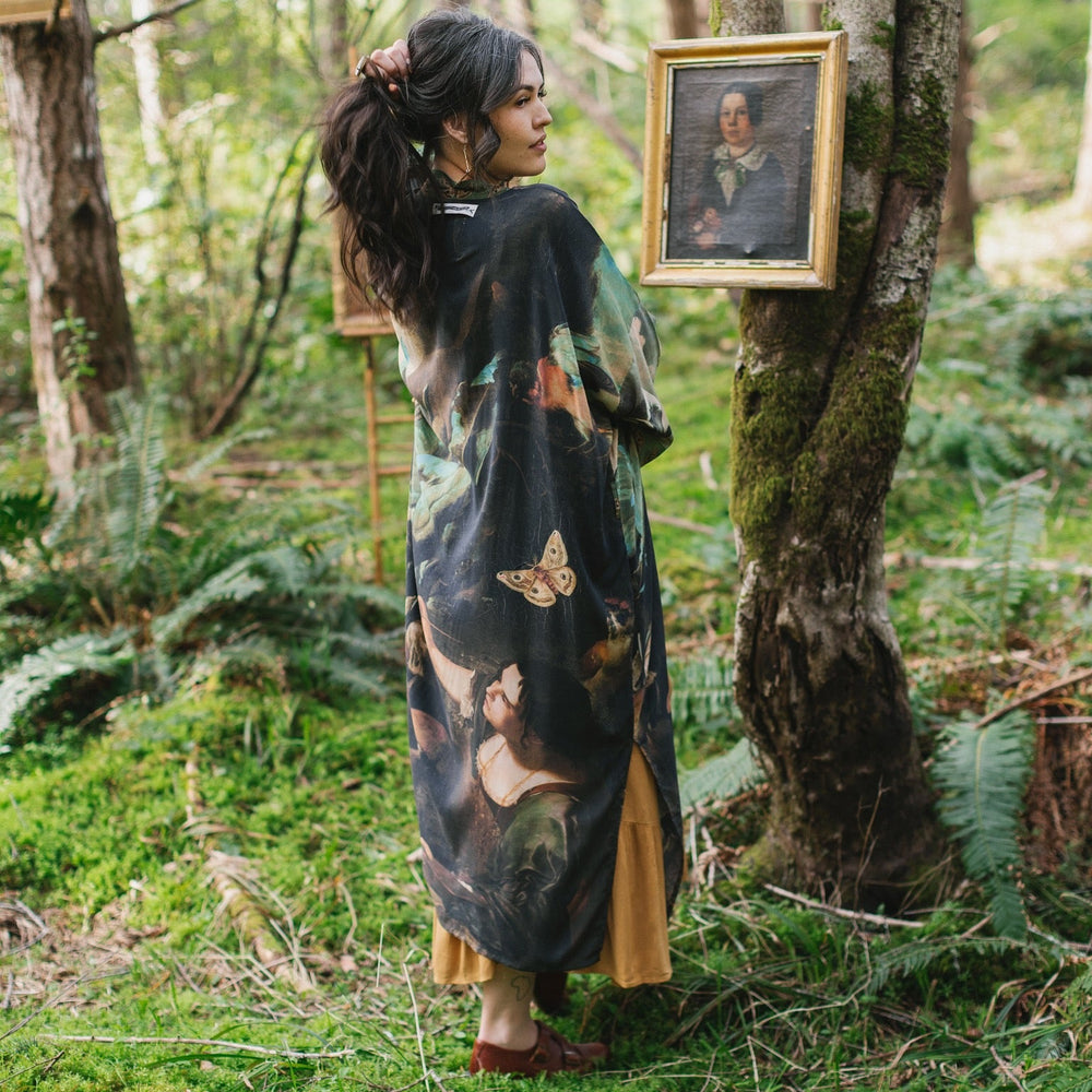 
                  
                    Model wearing the Heartwork Opera Duster featuring Artemisia Gentileschi’s self-portrait surrounded by forest, birds, and butterflies – Market of Stars.
                  
                