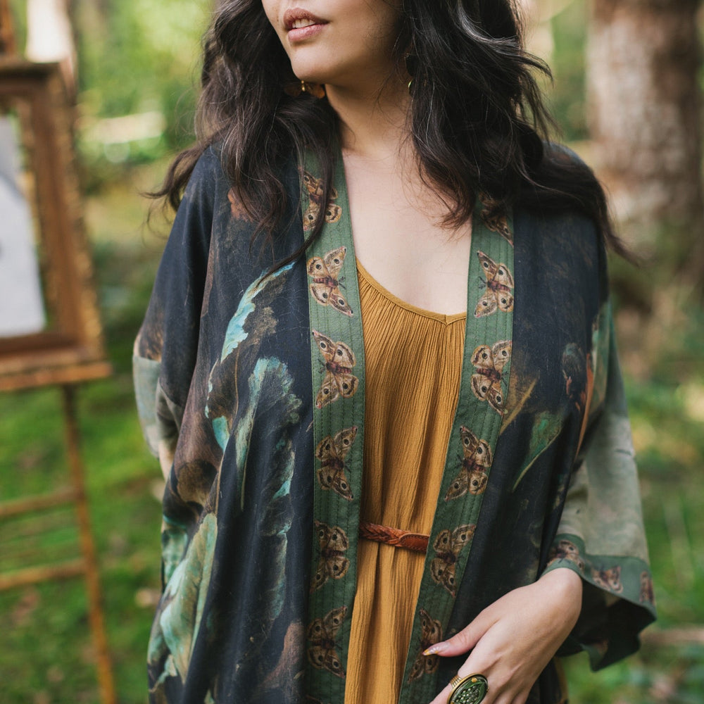 
                  
                    Model wearing the Heartwork Opera Duster featuring Artemisia Gentileschi’s self-portrait surrounded by forest, birds, and butterflies – Market of Stars.
                  
                