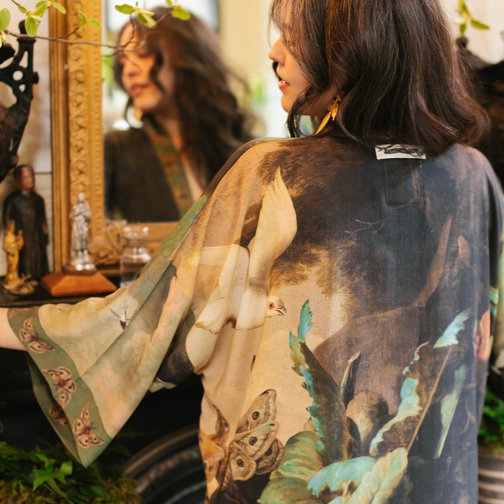 
                  
                    Model wearing the Heartwork Opera Duster featuring Artemisia Gentileschi’s self-portrait surrounded by forest, birds, and butterflies – Market of Stars.
                  
                