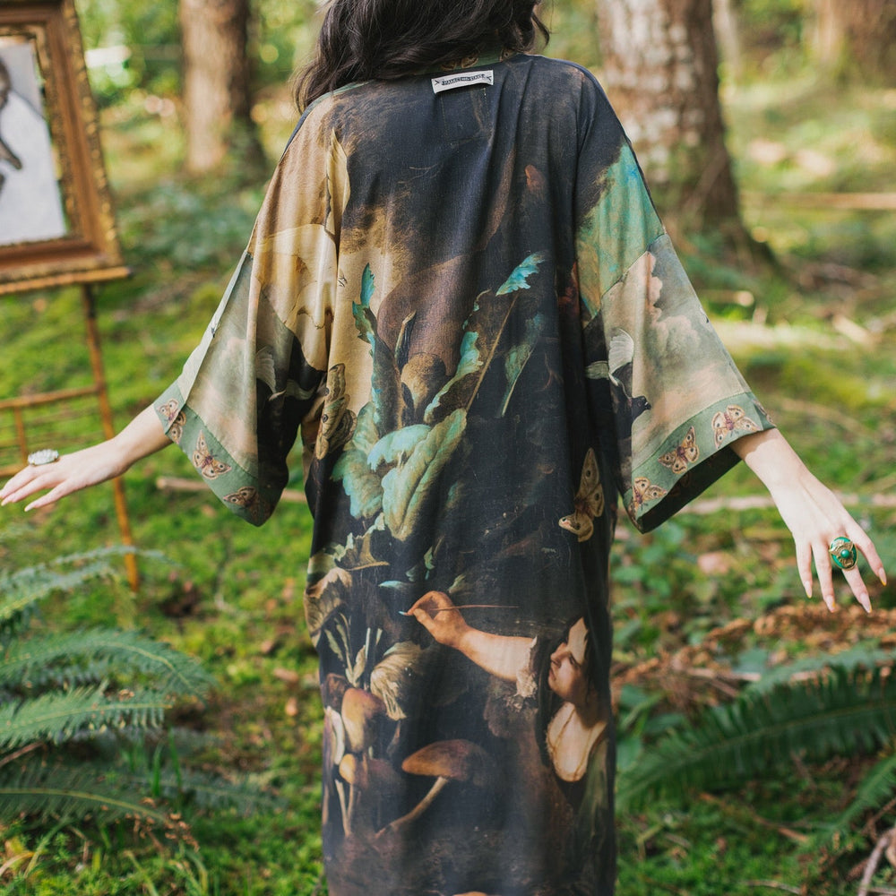 
                  
                    Model wearing the Heartwork Opera Duster featuring Artemisia Gentileschi’s self-portrait surrounded by forest, birds, and butterflies – Market of Stars.
                  
                