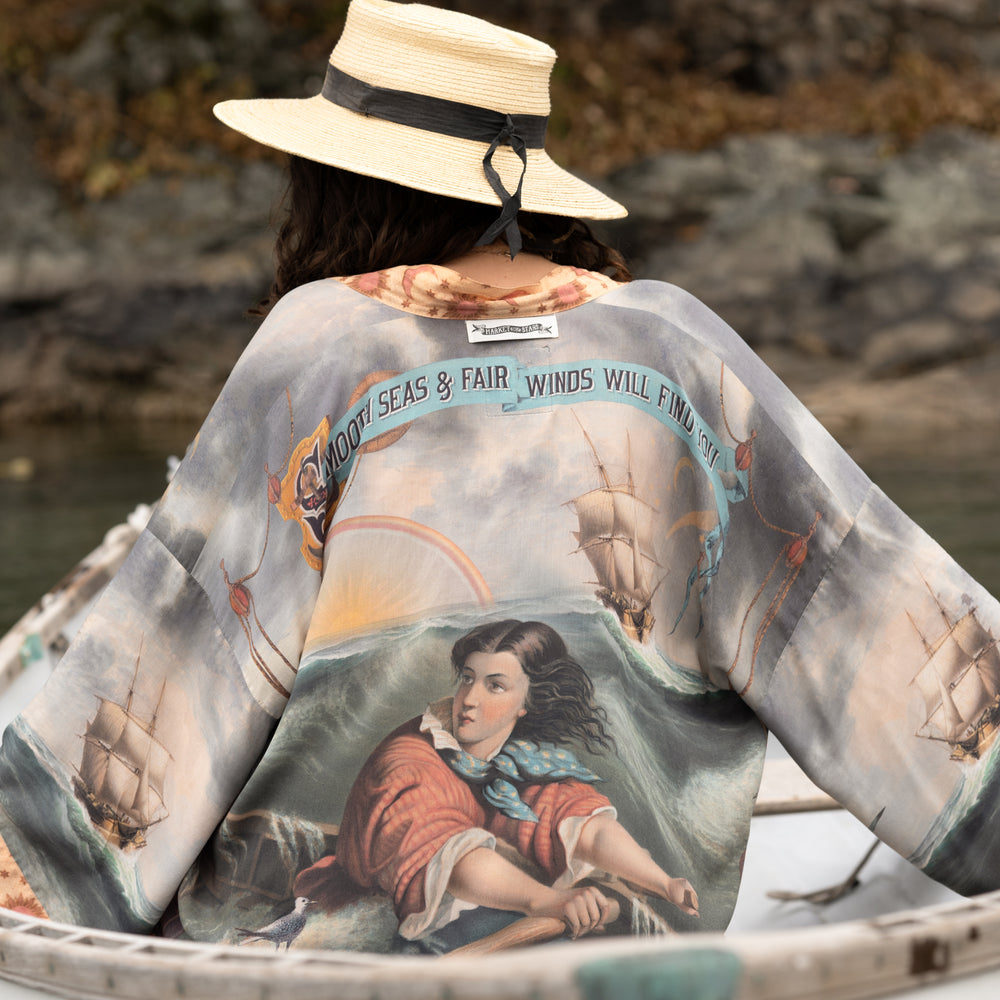 
                  
                    Model wearing the Hold Fast Pixie Duster featuring a Victorian woman rowing through a storm, seagulls, and rainbow horizon – Market of Stars.
                  
                