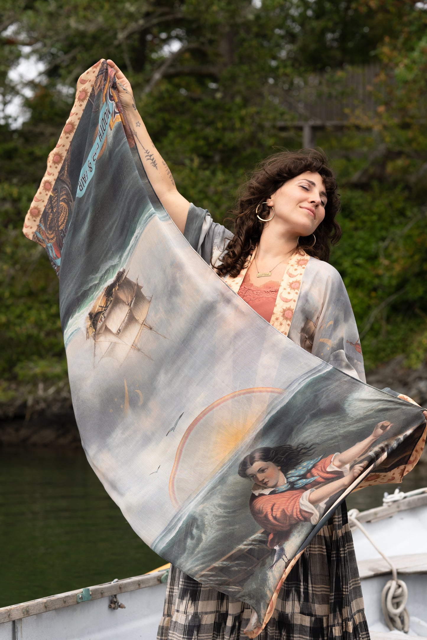 Model wearing the Hold Fast bamboo viscose scarf featuring a Victorian woman bravely rowing through a storm, seagulls, and rainbow horizon – Market of Stars.