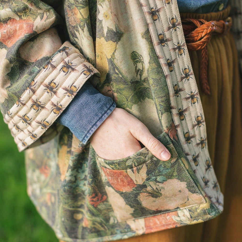 
                  
                    Model wearing the I Dream in Flowers Cottage Cardigan featuring painterly floral artwork and Victorian bumblebee trim, perfect for cozy layering – Market of Stars
                  
                