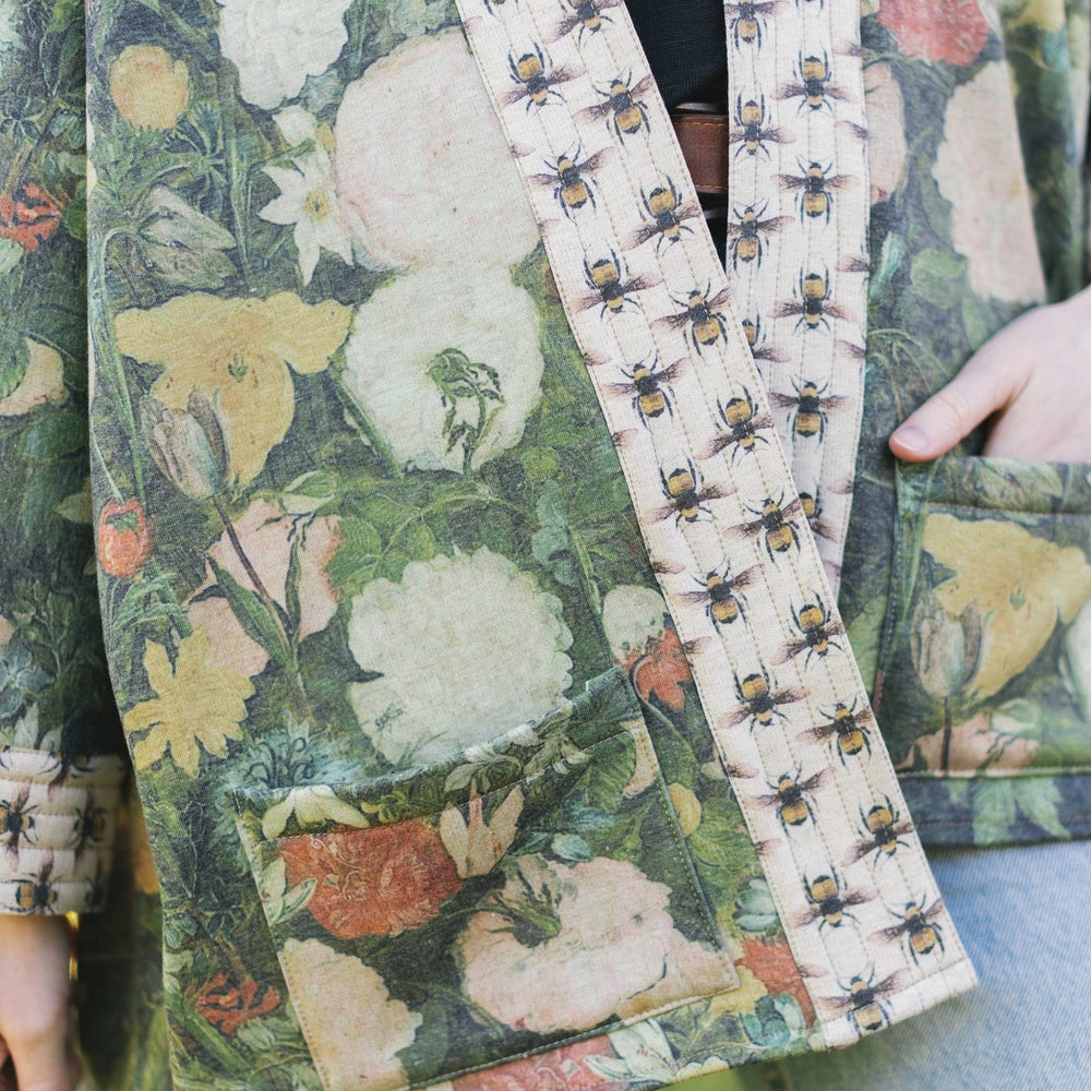
                  
                    Model wearing the I Dream in Flowers Cottage Cardigan featuring painterly floral artwork and Victorian bumblebee trim, perfect for cozy layering – Market of Stars
                  
                