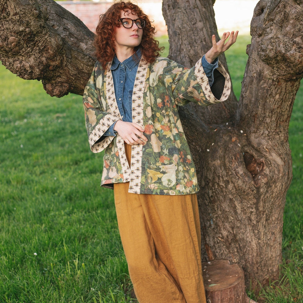 
                  
                    Model wearing the I Dream in Flowers Cottage Cardigan featuring painterly floral artwork and Victorian bumblebee trim, perfect for cozy layering – Market of Stars
                  
                