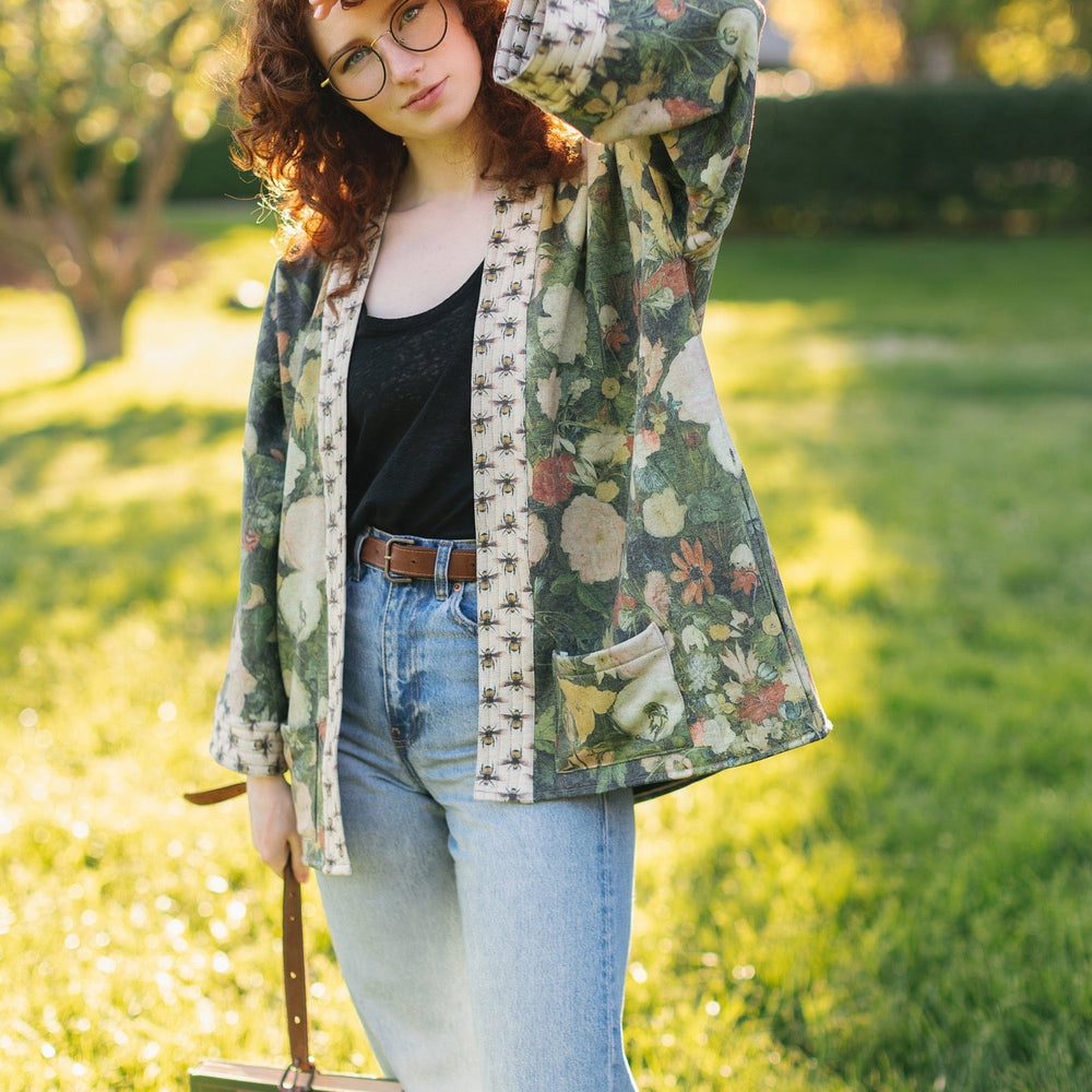 
                  
                    Model wearing the I Dream in Flowers Cottage Cardigan featuring painterly floral artwork and Victorian bumblebee trim, perfect for cozy layering – Market of Stars
                  
                