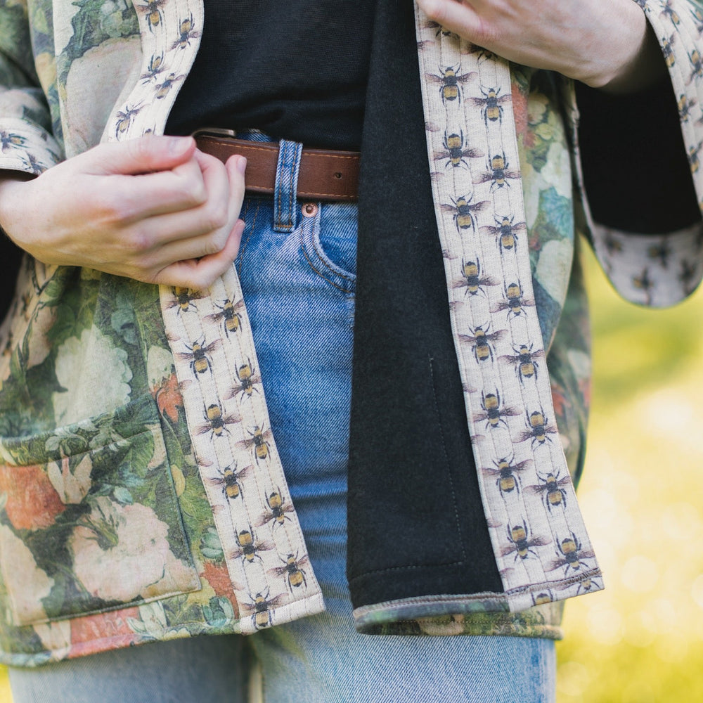 
                  
                    Model wearing the I Dream in Flowers Cottage Cardigan featuring painterly floral artwork and Victorian bumblebee trim, perfect for cozy layering – Market of Stars
                  
                