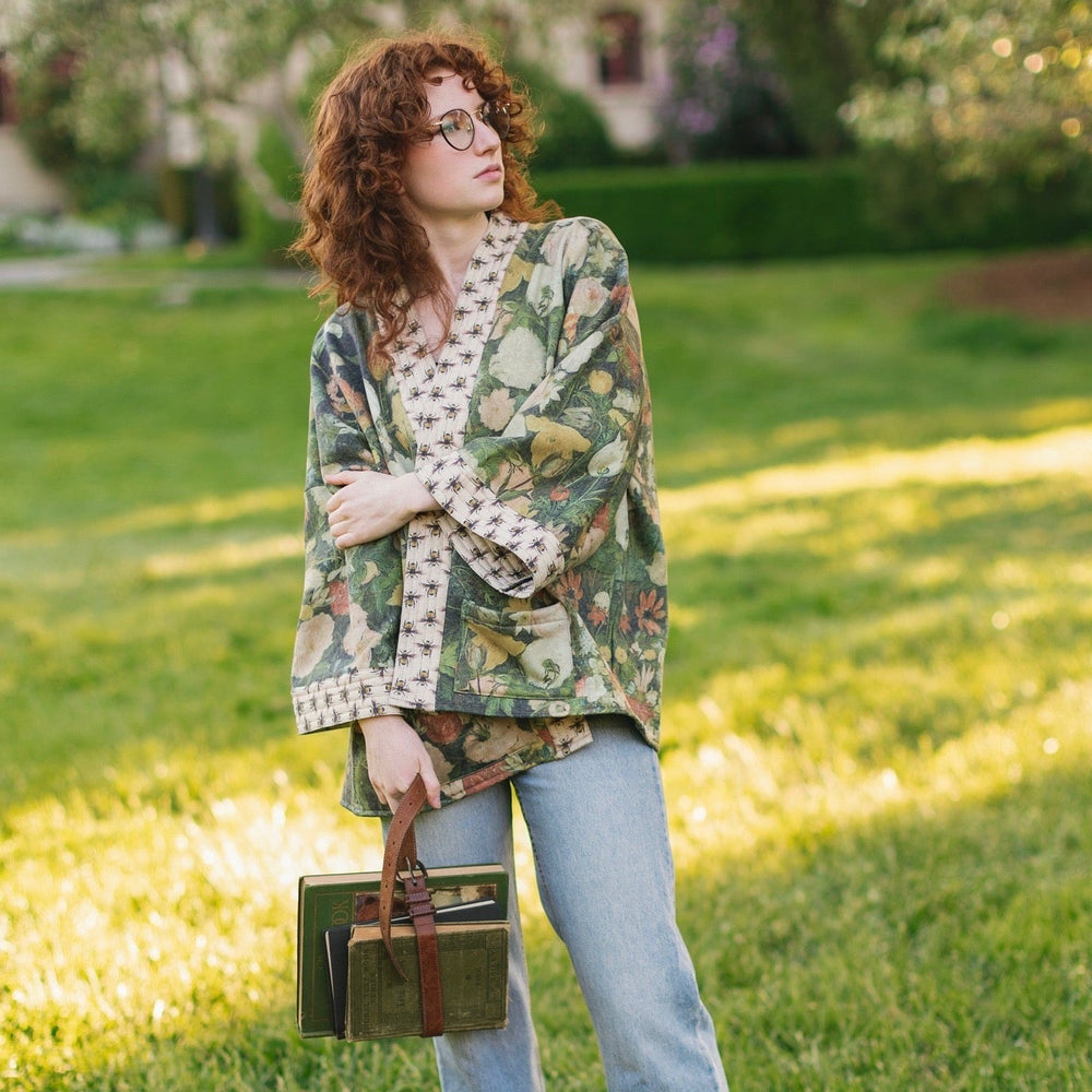 
                  
                    Model wearing the I Dream in Flowers Cottage Cardigan featuring painterly floral artwork and Victorian bumblebee trim, perfect for cozy layering – Market of Stars
                  
                