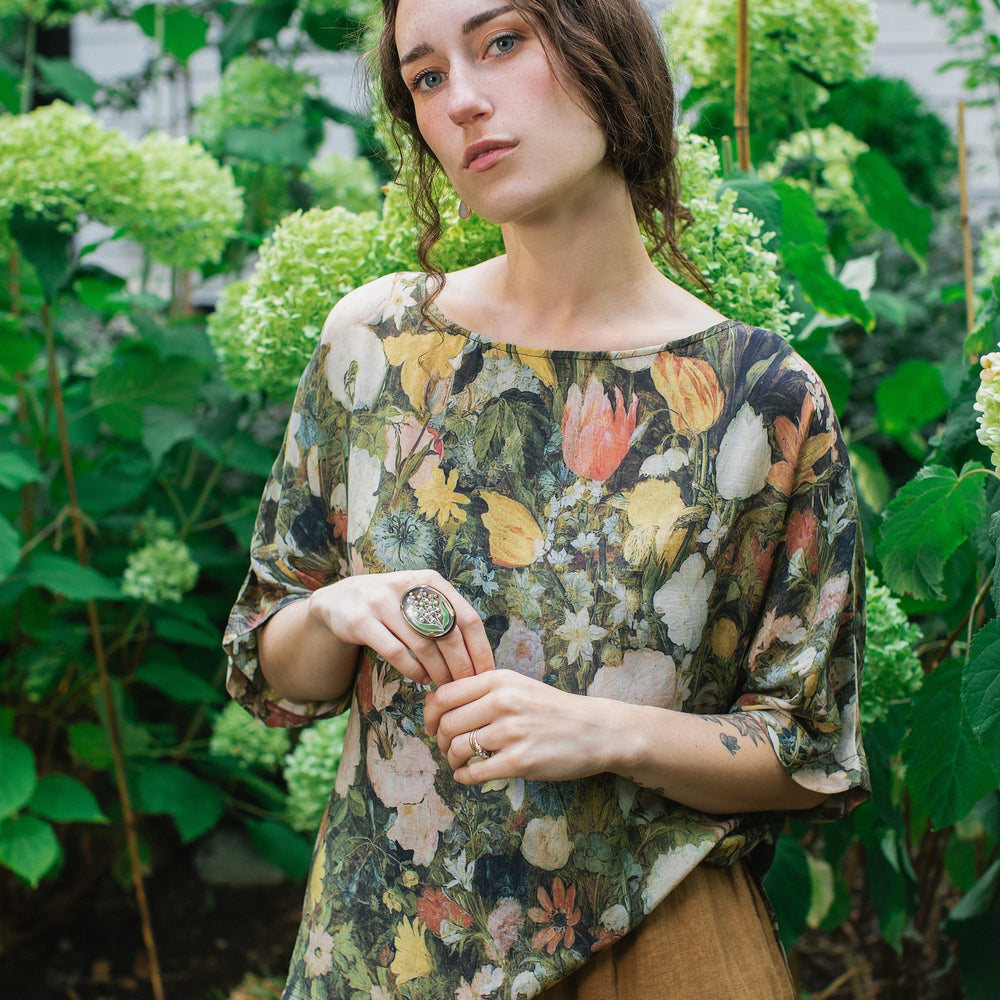 Model wearing the I Dream in Flowers Luxe Tee featuring painterly florals by Jan Brueghel and hidden bumblebee trim – Market of Stars.