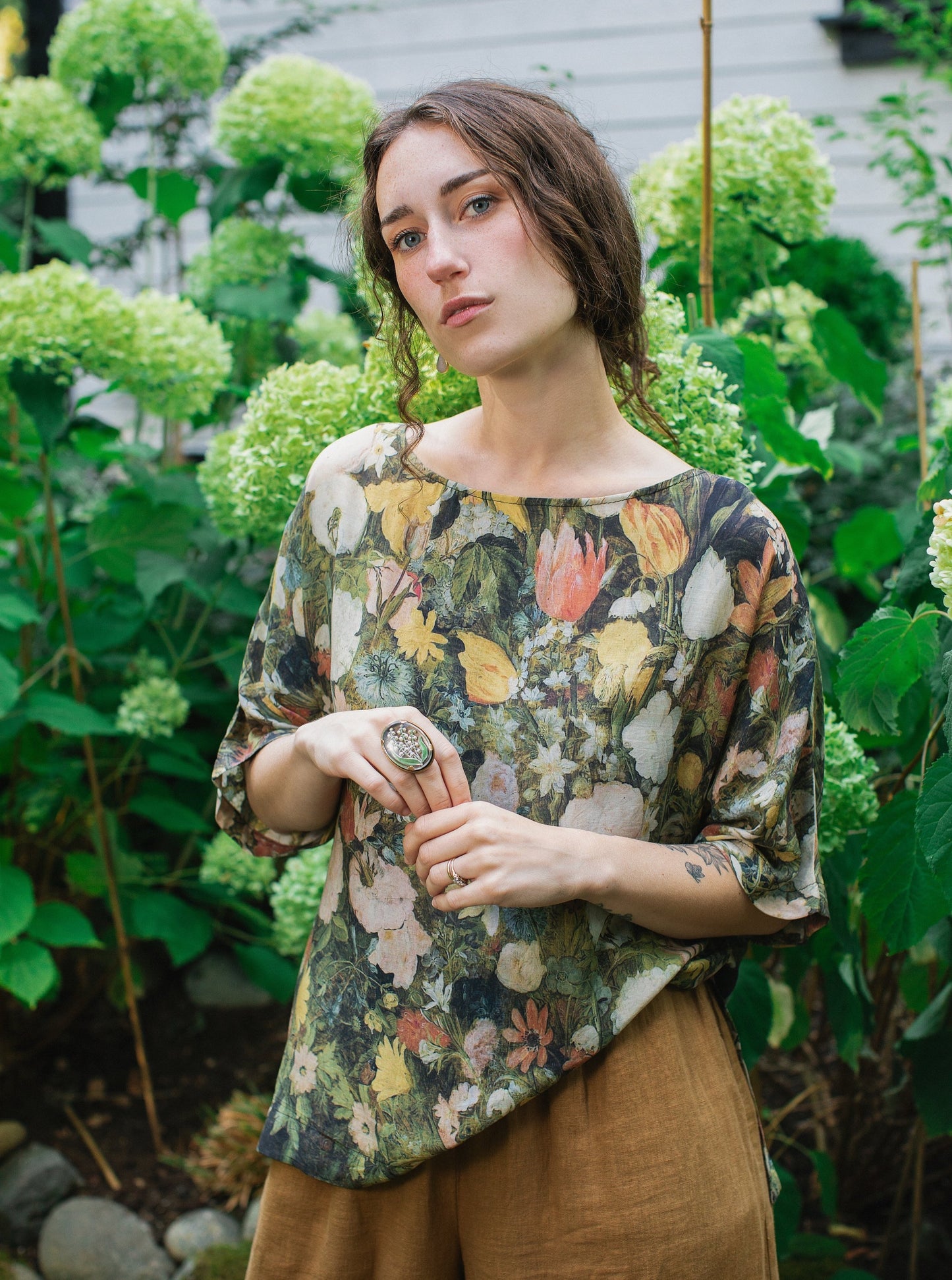 Model wearing the I Dream in Flowers Luxe Tee featuring painterly florals by Jan Brueghel and hidden bumblebee trim – Market of Stars.