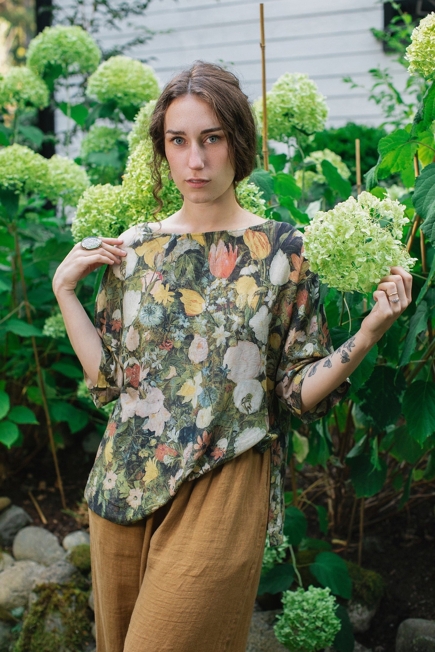 Model wearing the I Dream in Flowers Luxe Tee featuring painterly florals by Jan Brueghel and hidden bumblebee trim – Market of Stars.