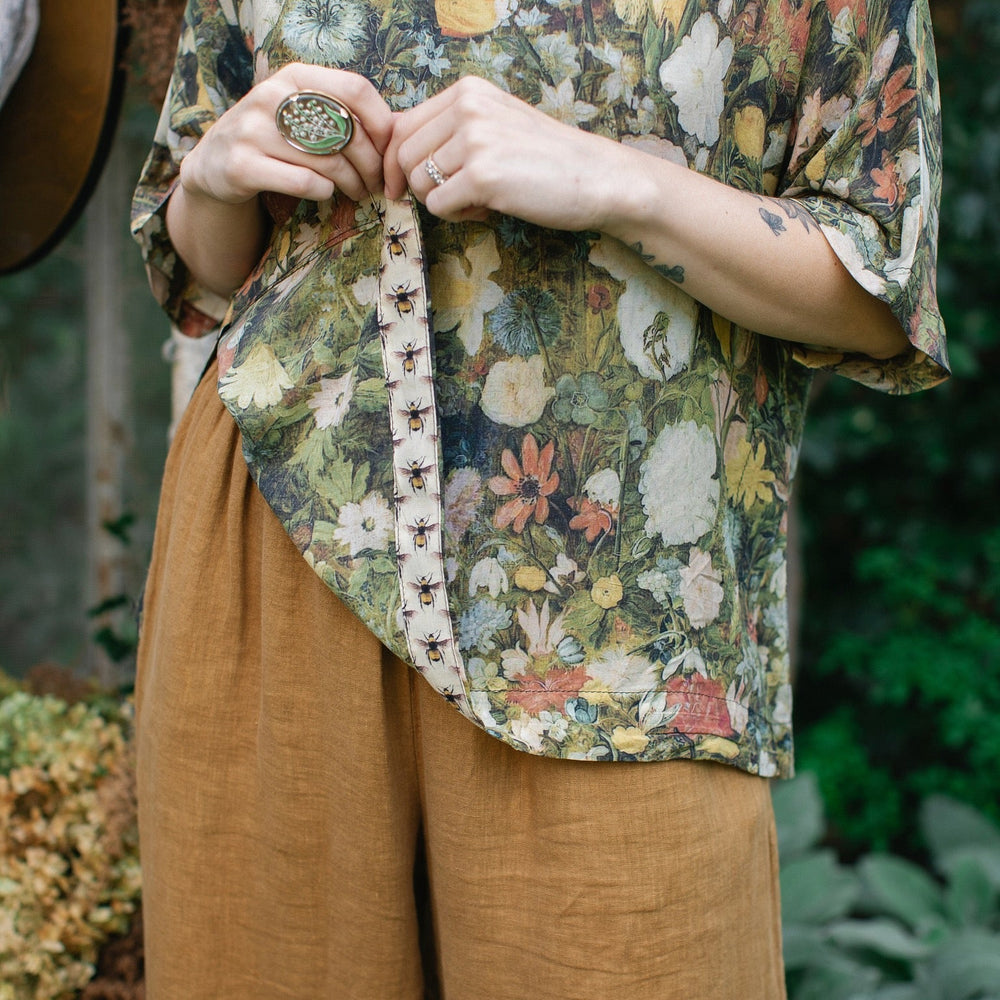 
                  
                    Model wearing the I Dream in Flowers Luxe Tee featuring painterly florals by Jan Brueghel and hidden bumblebee trim – Market of Stars.
                  
                