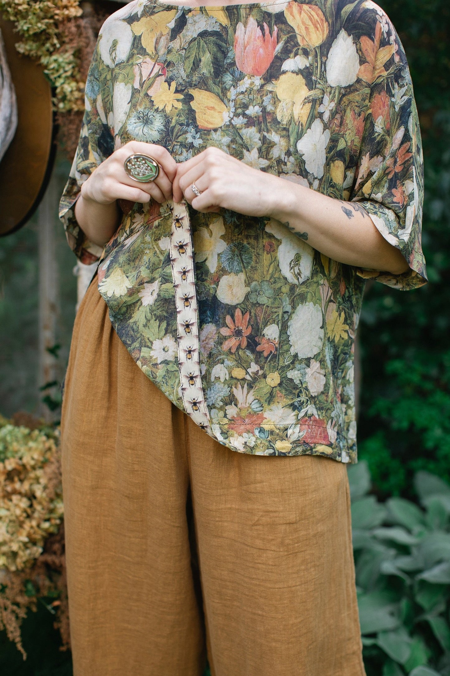 Model wearing the I Dream in Flowers Luxe Tee featuring painterly florals by Jan Brueghel and hidden bumblebee trim – Market of Stars.