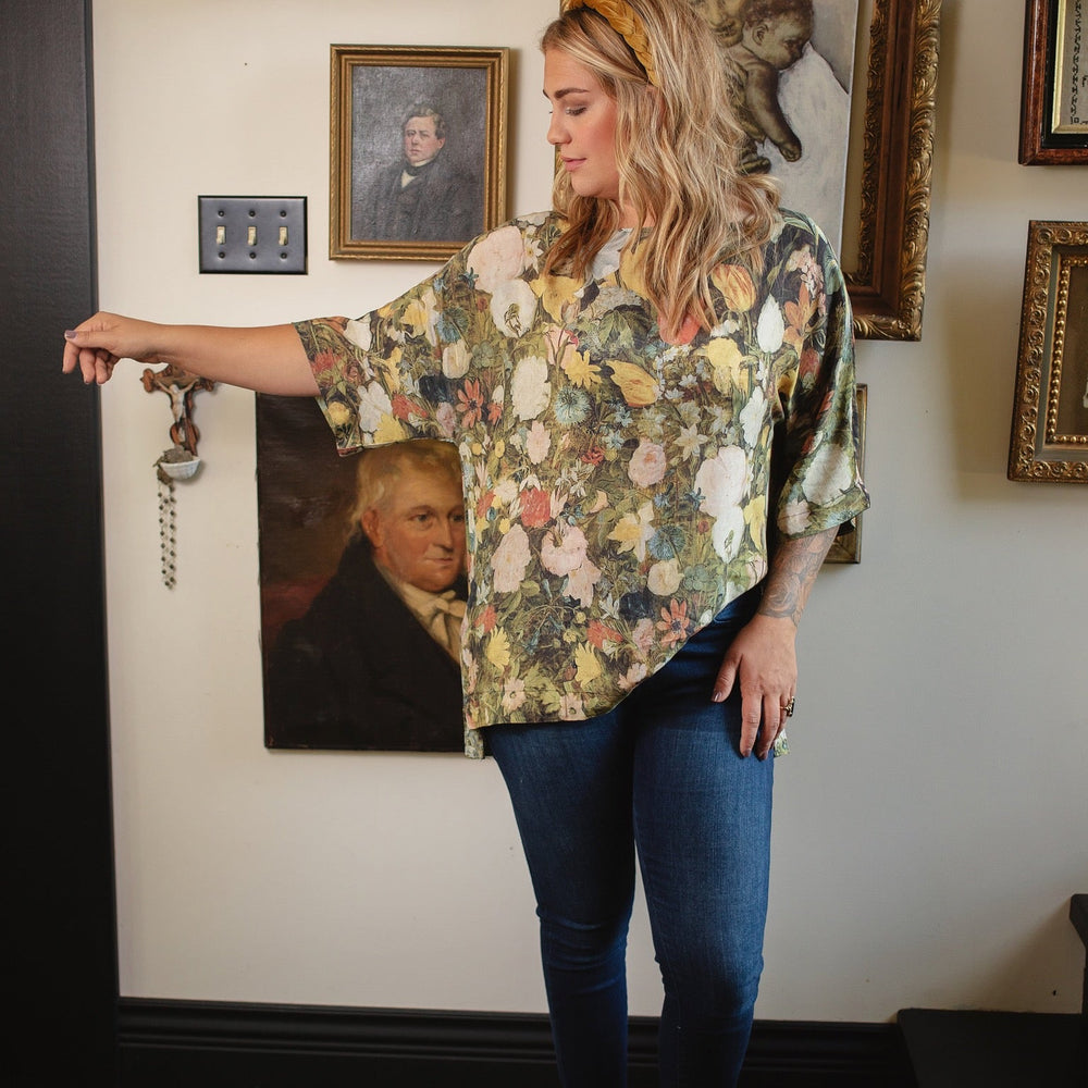 
                  
                    Model wearing the I Dream in Flowers Luxe Tee featuring painterly florals by Jan Brueghel and hidden bumblebee trim – Market of Stars.
                  
                