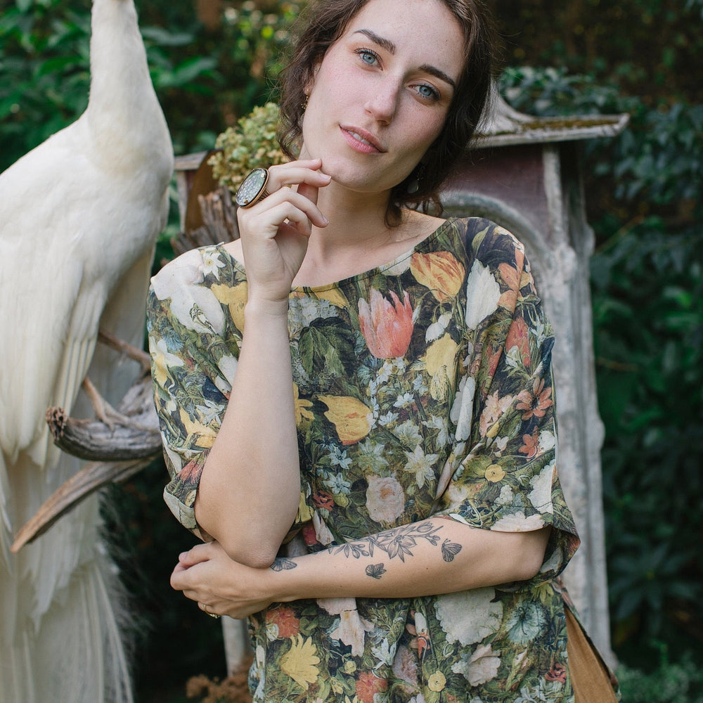 
                  
                    Model wearing the I Dream in Flowers Luxe Tee featuring painterly florals by Jan Brueghel and hidden bumblebee trim – Market of Stars.
                  
                