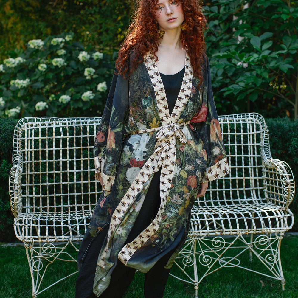
                  
                    Model wearing the I Dream in Flowers Opera Duster featuring floral oil painting by Jan Brueghel and Victorian bumblebee trim – Market of Stars.
                  
                
