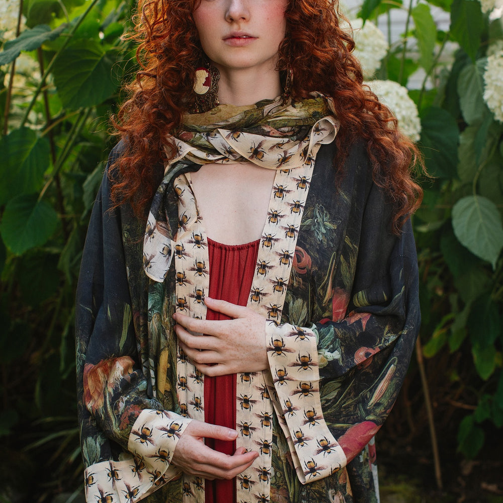 
                  
                    Model wearing the I Dream in Flowers Opera Duster featuring floral oil painting by Jan Brueghel and Victorian bumblebee trim – Market of Stars.
                  
                