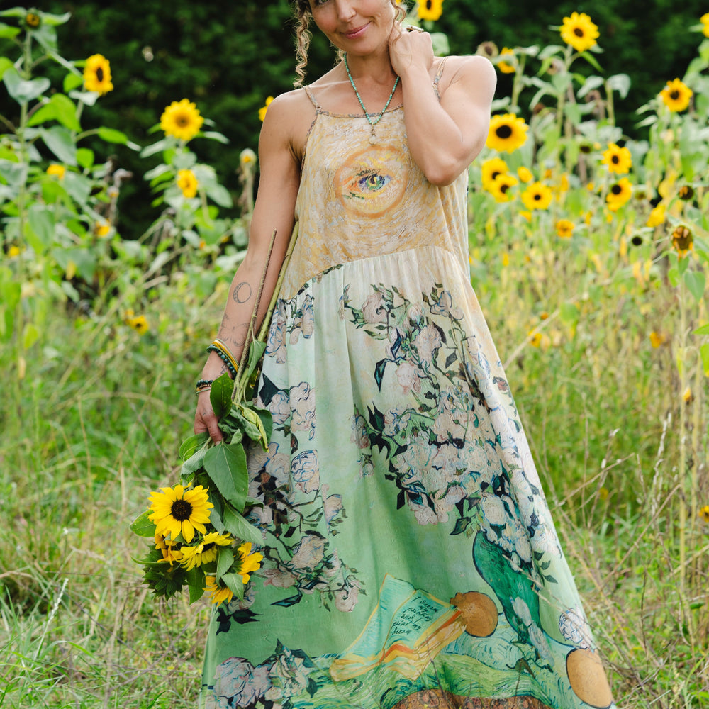 Model wearing bamboo viscose slip dress featuring Van Gogh artwork and quote, with painted blossoms, book, sun, and eye in rich sunny tones of jade and gold - Market of Stars
