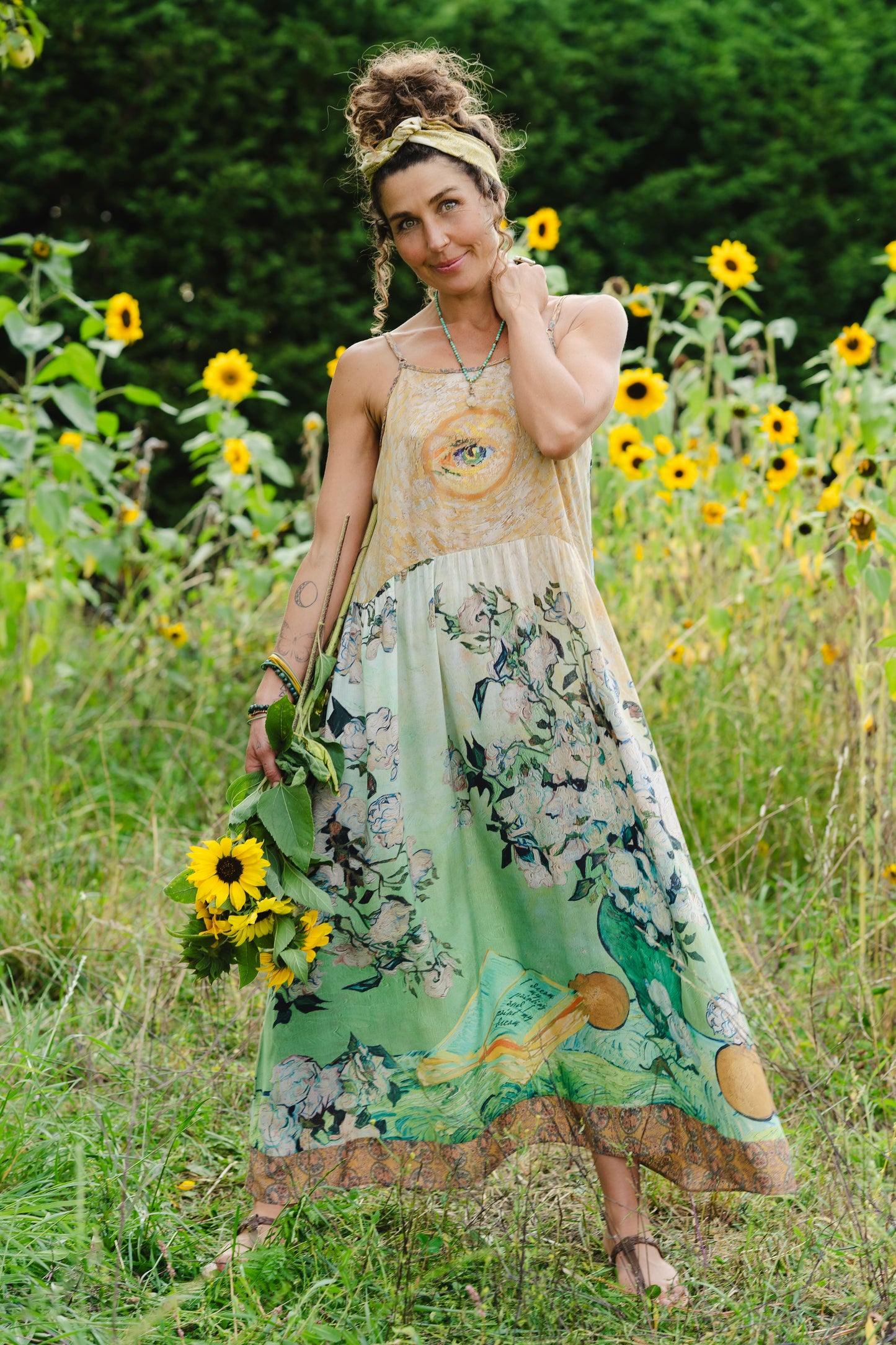 Model wearing bamboo viscose slip dress featuring Van Gogh artwork and quote, with painted blossoms, book, sun, and eye in rich sunny tones of jade and gold - Market of Stars