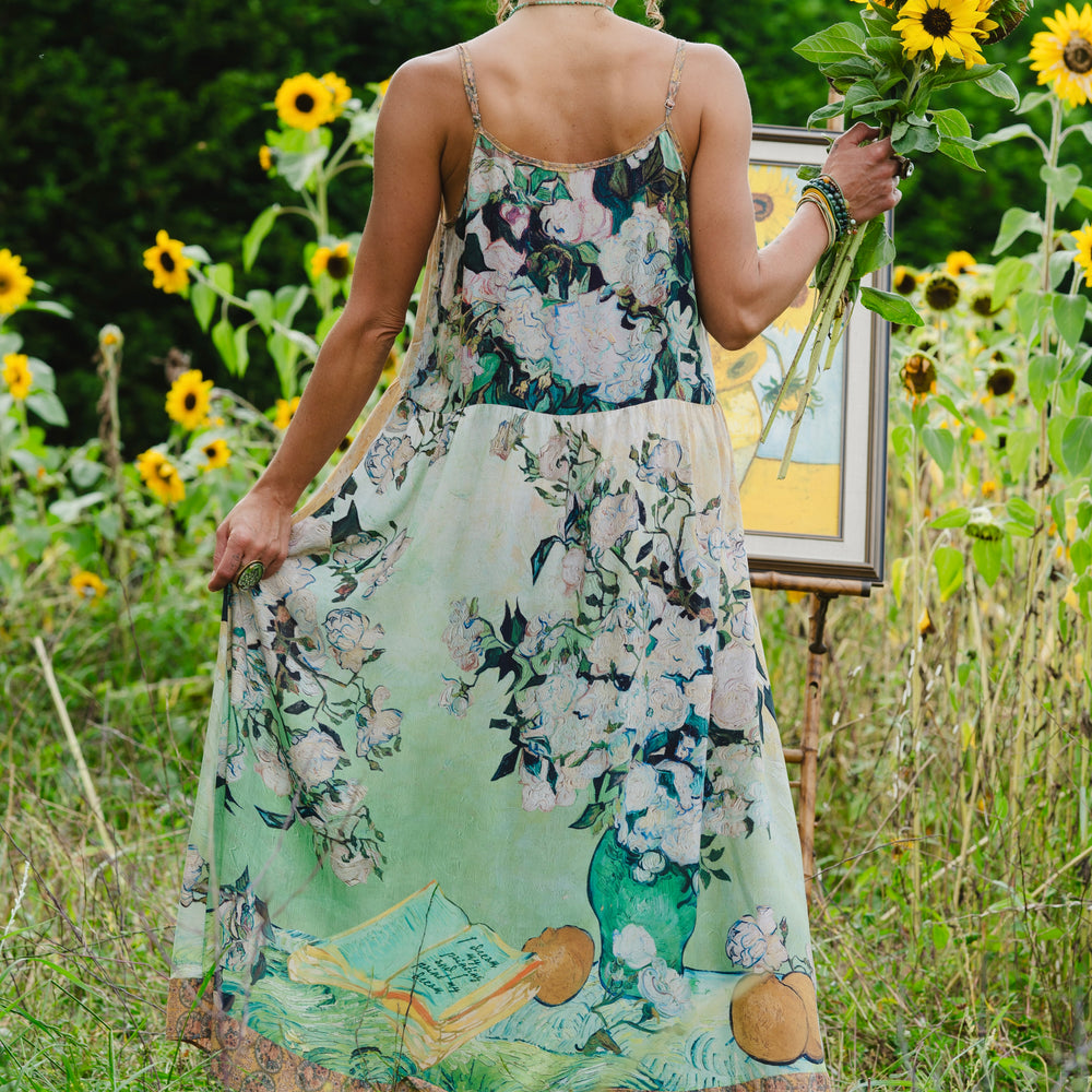 Model wearing bamboo viscose slip dress featuring Van Gogh artwork and quote, with painted blossoms, book, sun, and eye in rich sunny tones of jade and gold - Market of Stars