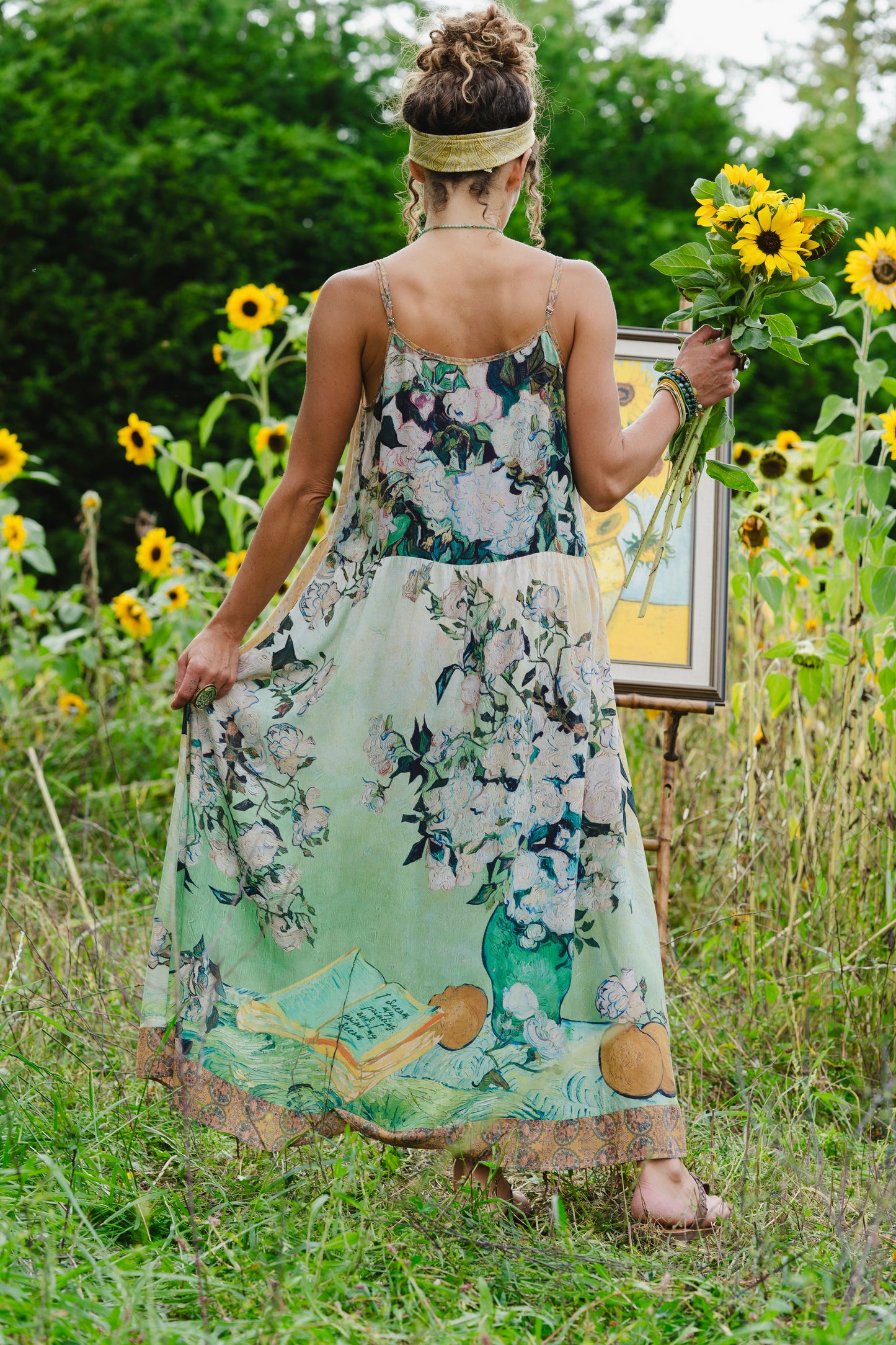 Model wearing bamboo viscose slip dress featuring Van Gogh artwork and quote, with painted blossoms, book, sun, and eye in rich sunny tones of jade and gold - Market of Stars