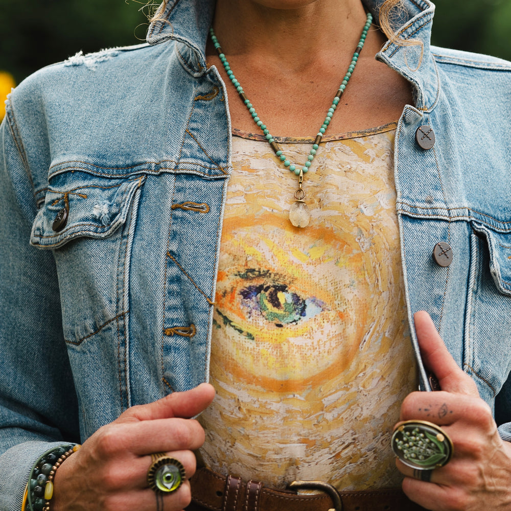 
                  
                    Model wearing bamboo viscose slip dress featuring Van Gogh artwork and quote, with painted blossoms, book, sun, and eye in rich sunny tones of jade and gold - Market of Stars
                  
                