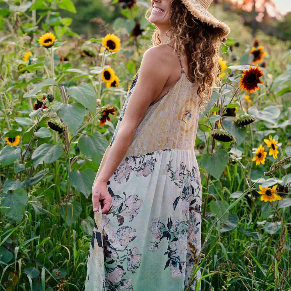
                  
                    Model wearing bamboo viscose slip dress featuring Van Gogh artwork and quote, with painted blossoms, book, sun, and eye in rich sunny tones of jade and gold - Market of Stars
                  
                