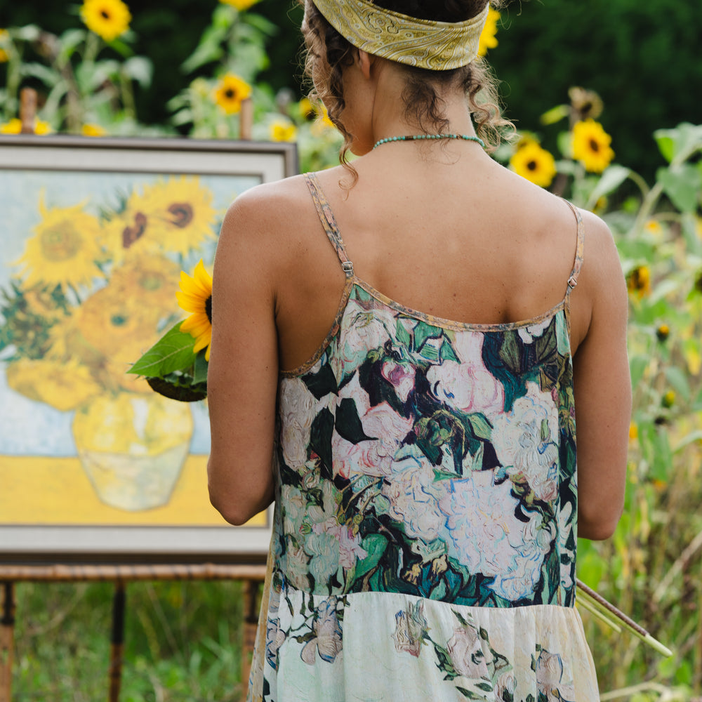 
                  
                    Model wearing bamboo viscose slip dress featuring Van Gogh artwork and quote, with painted blossoms, book, sun, and eye in rich sunny tones of jade and gold - Market of Stars
                  
                