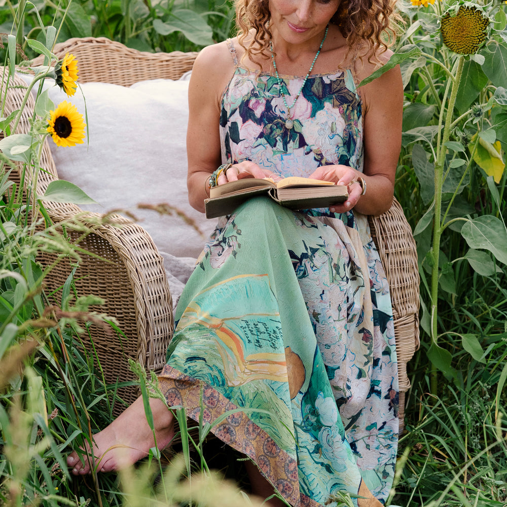 
                  
                    Model wearing bamboo viscose slip dress featuring Van Gogh artwork and quote, with painted blossoms, book, sun, and eye in rich sunny tones of jade and gold - Market of Stars
                  
                