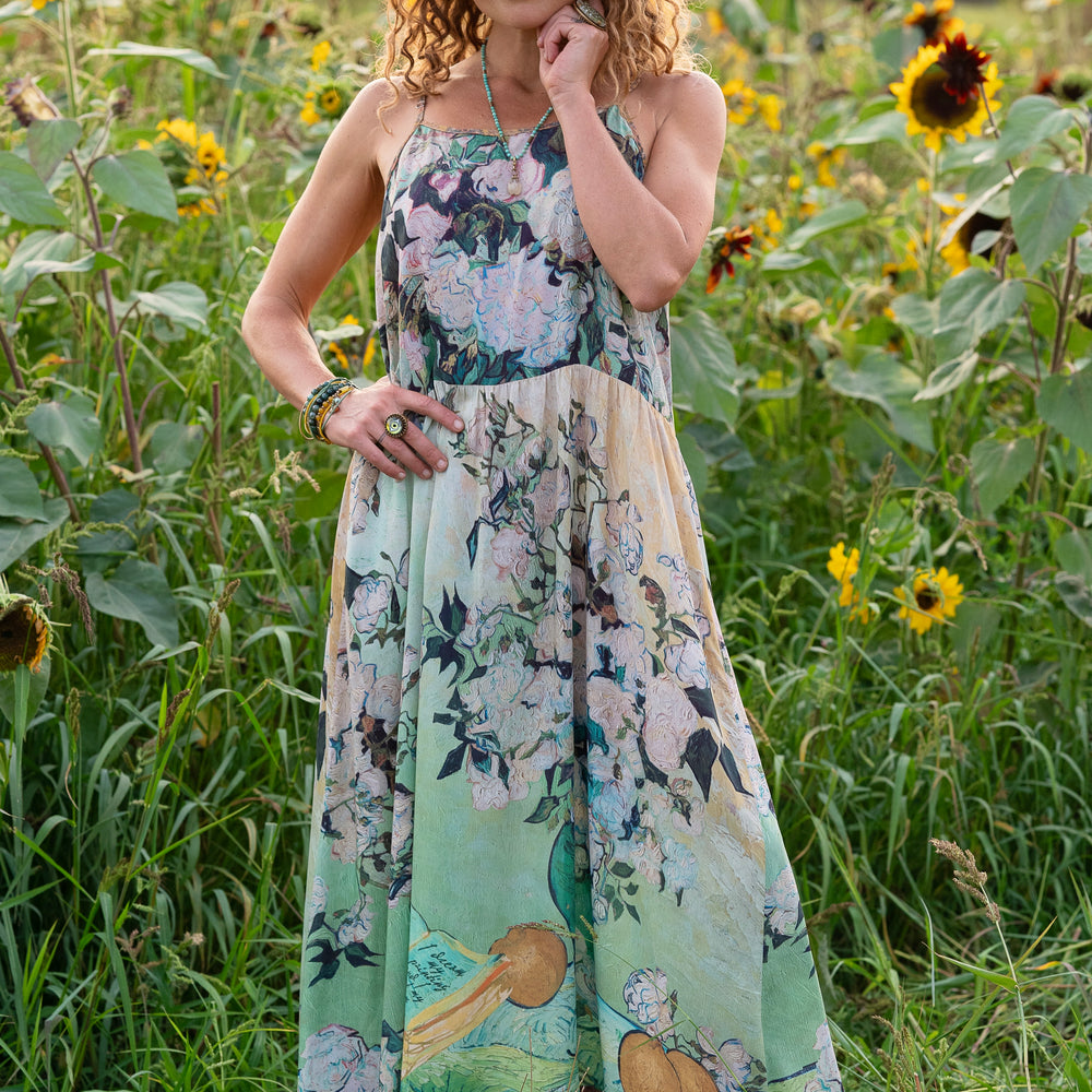 
                  
                    Model wearing bamboo viscose slip dress featuring Van Gogh artwork and quote, with painted blossoms, book, sun, and eye in rich sunny tones of jade and gold - Market of Stars
                  
                