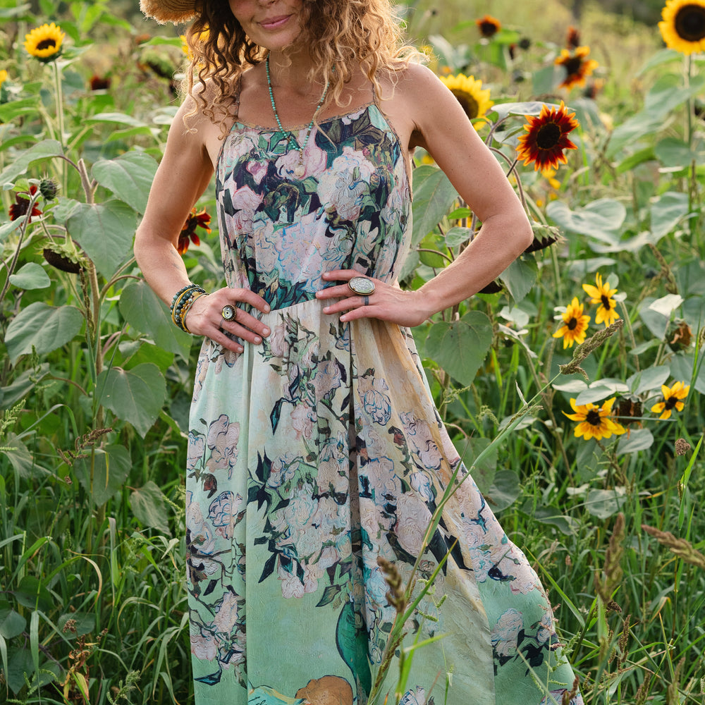 
                  
                    Model wearing bamboo viscose slip dress featuring Van Gogh artwork and quote, with painted blossoms, book, sun, and eye in rich sunny tones of jade and gold - Market of Stars
                  
                