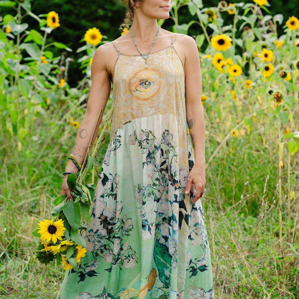 
                  
                    Model wearing bamboo viscose slip dress featuring Van Gogh artwork and quote, with painted blossoms, book, sun, and eye in rich sunny tones of jade and gold - Market of Stars
                  
                