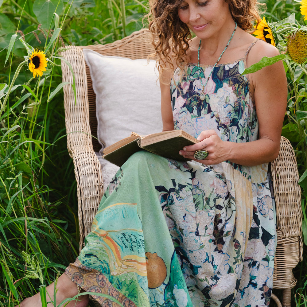 
                  
                    Model wearing bamboo viscose slip dress featuring Van Gogh artwork and quote, with painted blossoms, book, sun, and eye in rich sunny tones of jade and gold - Market of Stars
                  
                
