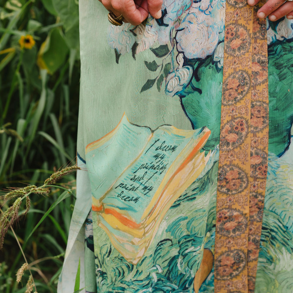 
                  
                    Model wearing long kimono duster featuring Van Gogh artwork and quote, with painted blossoms, book, sun, and eye in rich tones of jade and gold - Market of Stars
                  
                
